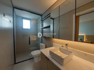 Banheiro moderno com box de vidro e louças brancas.