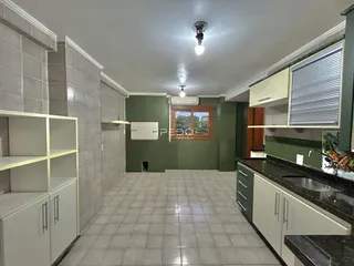 Interior de um corredor com piso de cerâmica e armários brancos.