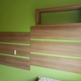 Parede decorada com painéis de madeira clara em um ambiente interno.