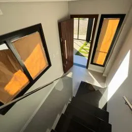 Vista de um corredor com escadaria escura em uma residência.