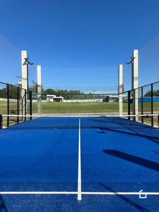 Imagem de uma quadra esportiva azul ao ar livre em uma propriedade.