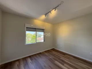 Ambiente interno com piso de madeira e janela.