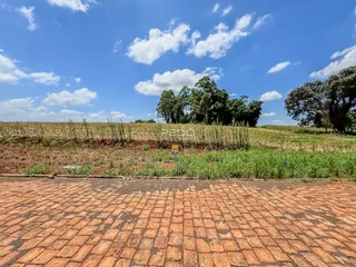 Vista da propriedade com um campo aberto e vegetação ao fundo.
