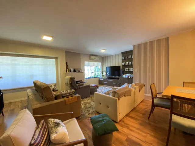 Sala de estar com sofás e piso de madeira clara.