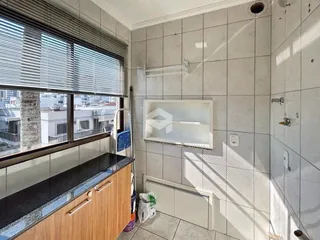 Foto de um banheiro com janela e revestimento de azulejos claros.