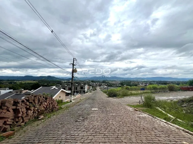Vista de uma rua pavimentada em Lajeado, Brasil, com colinas ao fundo.