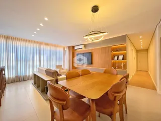 Sala de jantar com mesa de madeira e ambiente iluminado.