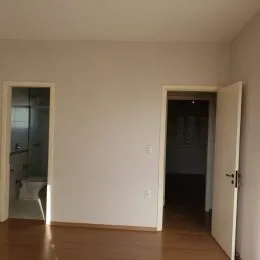 Hall de entrada com piso de madeira e paredes brancas.