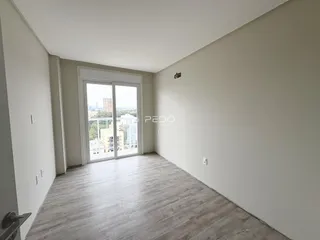 Vista interna de um ambiente com piso de madeira clara e porta de vidro.