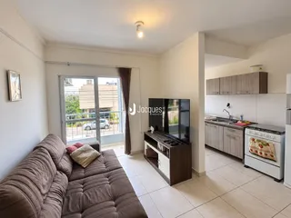 Sala de estar com vista para o exterior e cozinha integrada em apartamento.