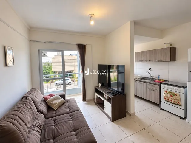 Sala de estar com vista para o exterior e cozinha integrada em apartamento.