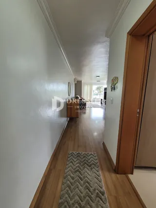 Corredor interno de uma residência com piso de madeira clara.