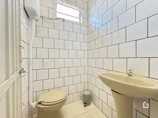 Foto de um banheiro com revestimento de azulejos brancos.