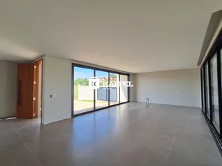 Esta é uma sala ampla com piso de concreto e grandes portas de vidro.