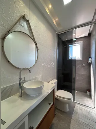 Interior de um banheiro moderno com bancada branca e azulejos claros.