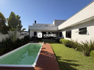 Foto da fachada de uma residência com piscina e jardim em Lajeado.