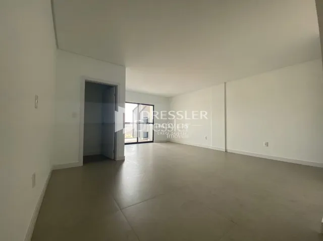 Interior de um espaço amplo com paredes brancas e piso claro.
