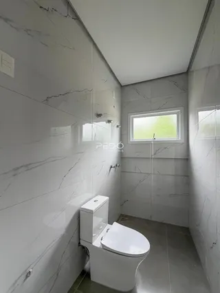 Banheiro com revestimento de azulejos brancos e piso claro.