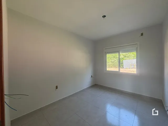 Vista interna de um cômodo com paredes brancas e piso de cerâmica.