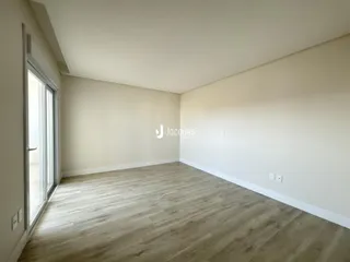 Ambiente interno de uma sala com piso de madeira clara e grandes janelas.