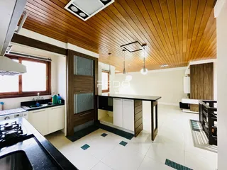 Interior de uma sala de estar com teto de madeira e piso claro.