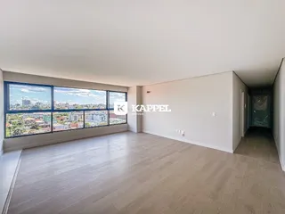 Uma sala ampla com grandes janelas que oferecem uma vista da cidade.