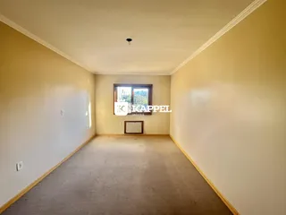 Corredor interno com piso de carpete e janela no final da sala.