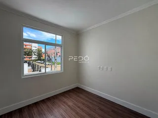 Ambiente interno com piso de madeira e grande janela de vista para a rua.