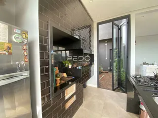 Vista da cozinha com revestimento de tijolos escuros e portas de vidro.
