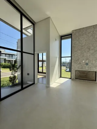 Vista interna de um ambiente com grandes portas de vidro e paredes brancas.
