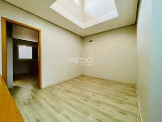 Interior de um ambiente com piso de madeira clara e paredes brancas.