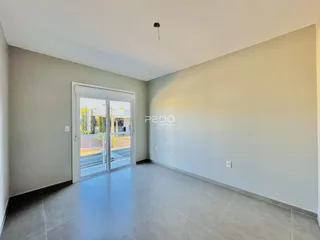 Interior de uma sala com piso de cerâmica e porta de vidro abrindo para o exterior.