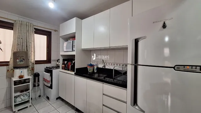 Cozinha moderna com armários brancos e bancadas escuras.