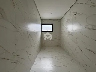 Corredor interno com revestimento em mármore branco nas paredes e piso.