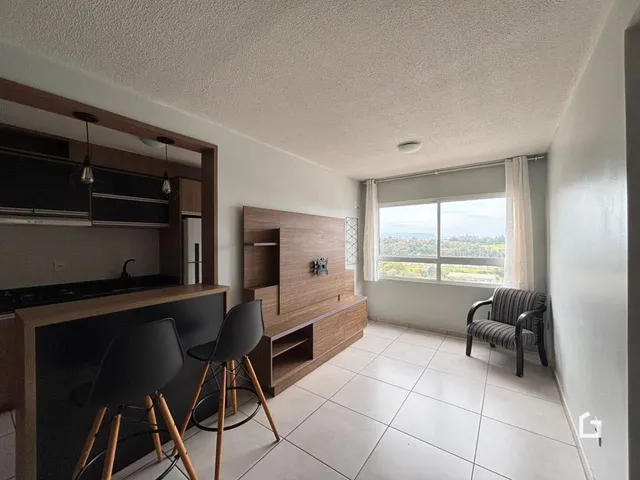 Sala de estar com piso de cerâmica e móveis de madeira em Lajeado.