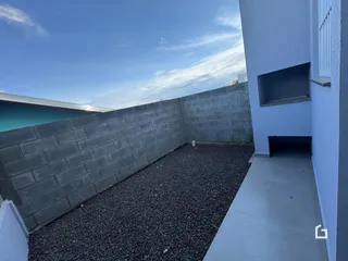 Vista lateral de um pátio com muro de concreto e área de terra preta.