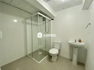 Foto de um banheiro com box de vidro, vaso sanitário e pia brancos.