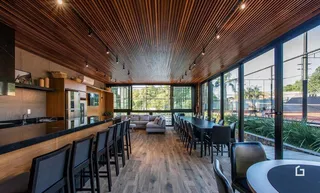 A sala de jantar possui um teto de madeira e grandes janelas que dão vista para o exterior.