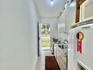 Vista de um corredor interno que leva à cozinha e a uma porta de acesso ao jardim.