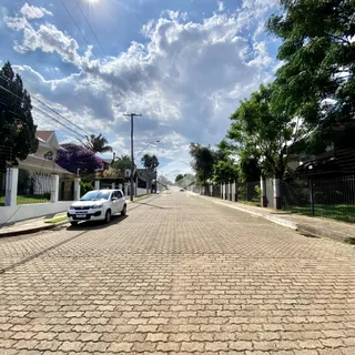 Uma rua pavimentada com casas e árvores em Lajeado.