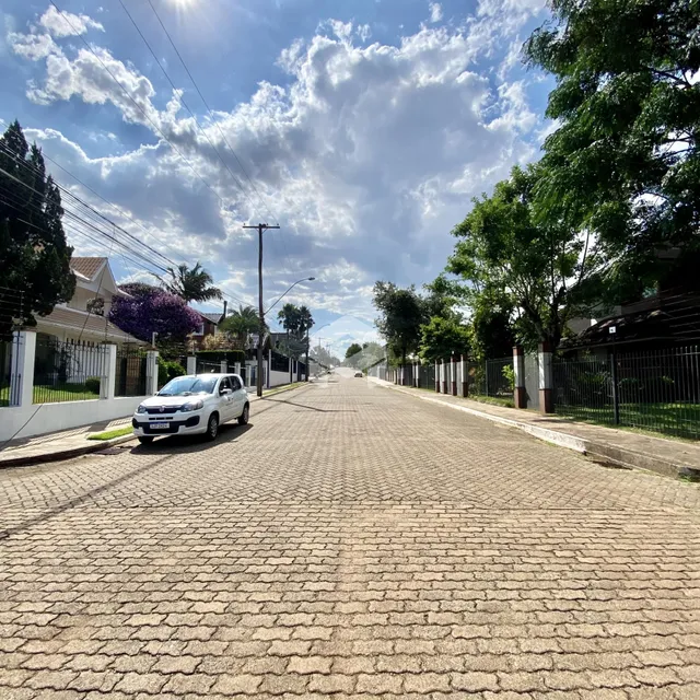 Uma rua pavimentada com casas e árvores em Lajeado.