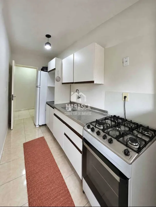 Vista interna de uma cozinha com armários brancos e piso claro.
