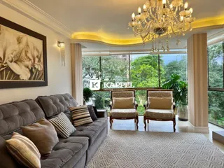 Sala de estar com sofá grande e vista para a vegetação externa.