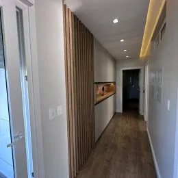 Corredor interno com piso de madeira e paredes claras.