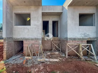 Fachada de uma residência em construção com alvenaria aparente na base.