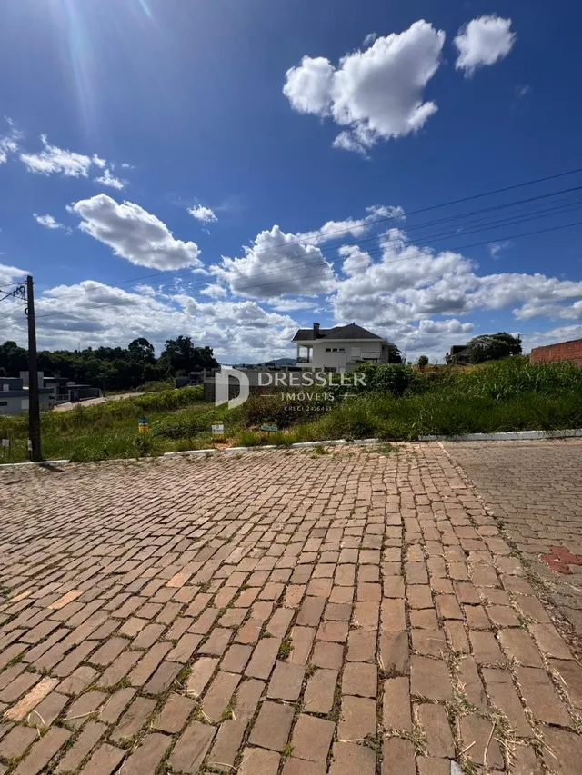 Vista de um pátio pavimentado com tijolos no exterior de uma propriedade.