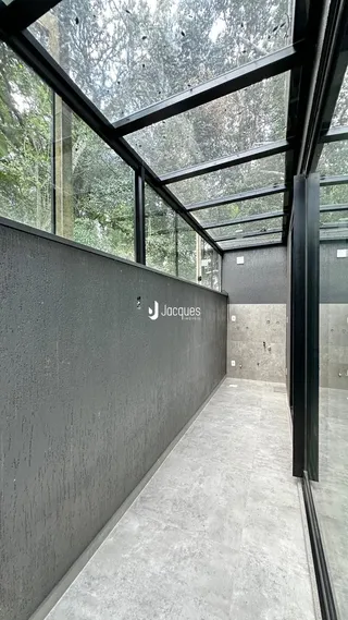 Corredor com grandes janelas e estrutura metálica moderna.