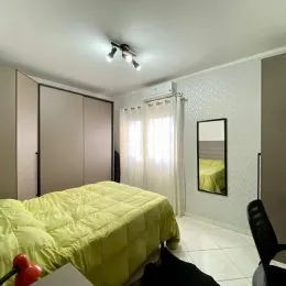 Quarto com cama de cor verde clara e paredes brancas.