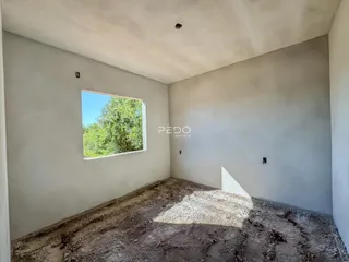 Foto de um cômodo interno com paredes brancas e piso de terra.