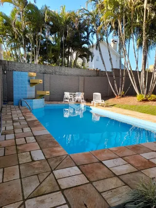 Foto de uma piscina externa com deck e vegetação em Lajeado.